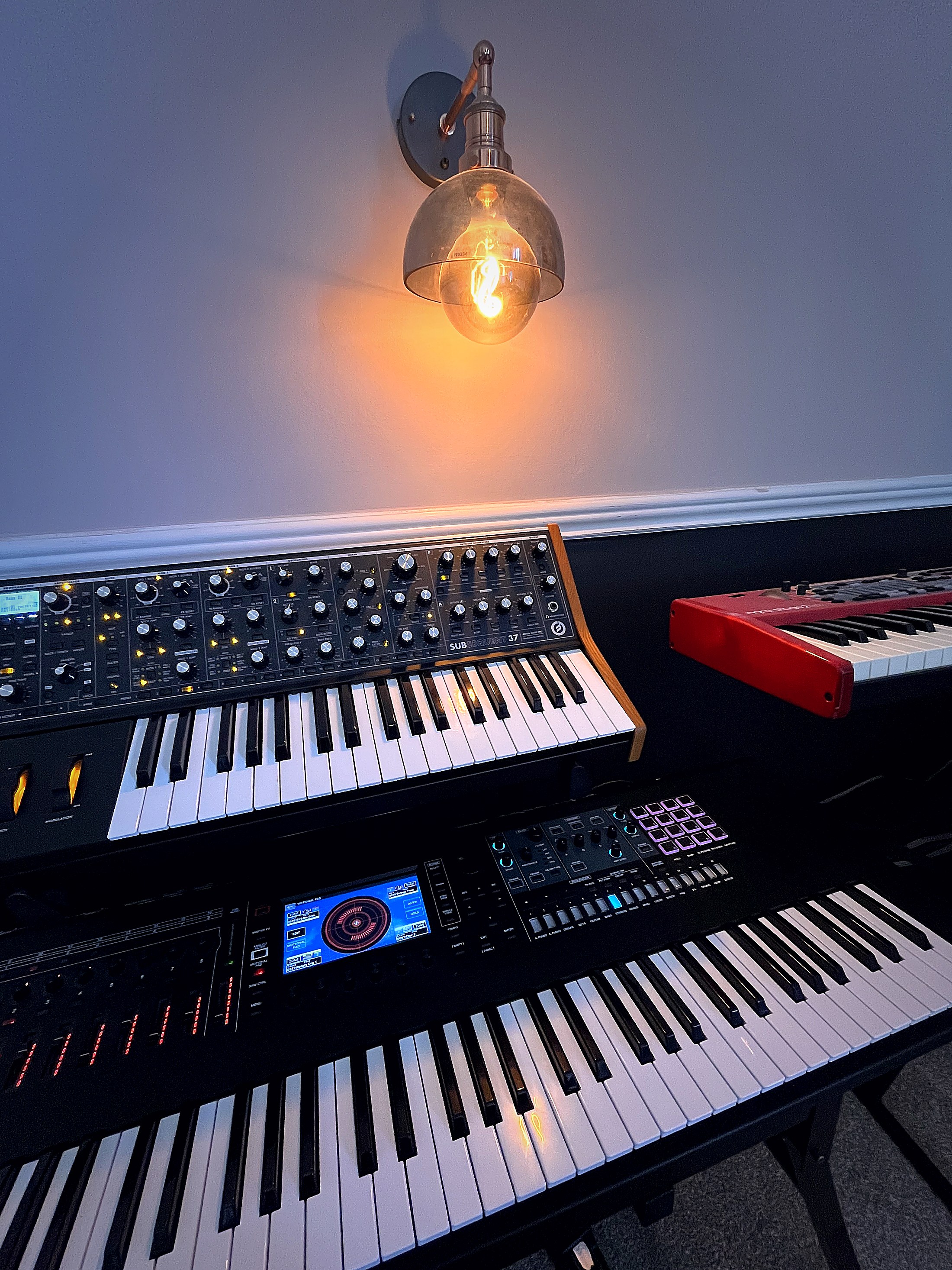 The studio — synth stack with warm tungsten light